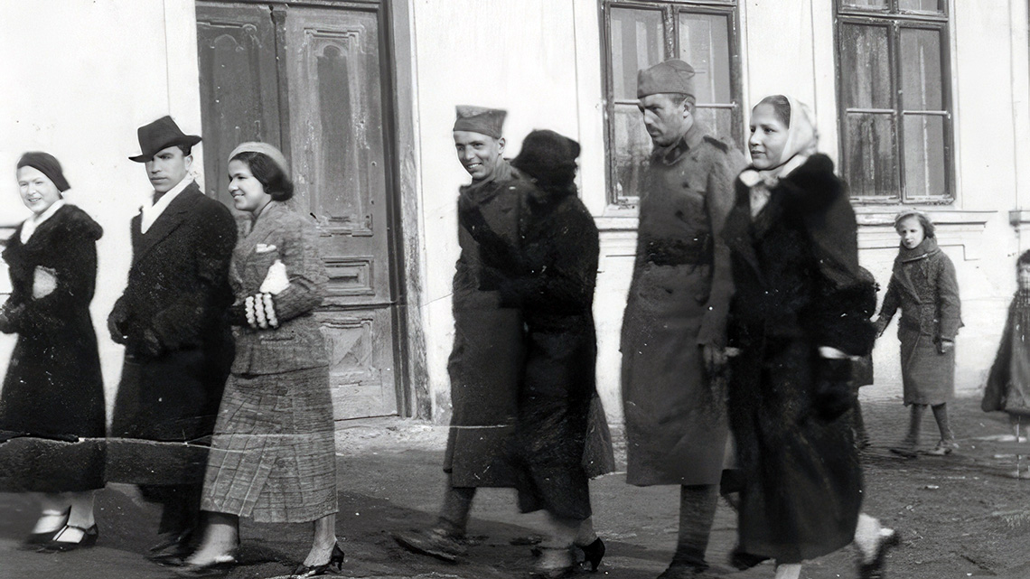 The entrance to the building from the main street "State People's School" was photographed on Christmas, January 7, 1936. Young married couples walked in an unknown direction. Among them was Milan Stančić-Uča with his fiancée, who spent the Christmas holidays in Kuman after returning from leave with the Yugoslav army. 